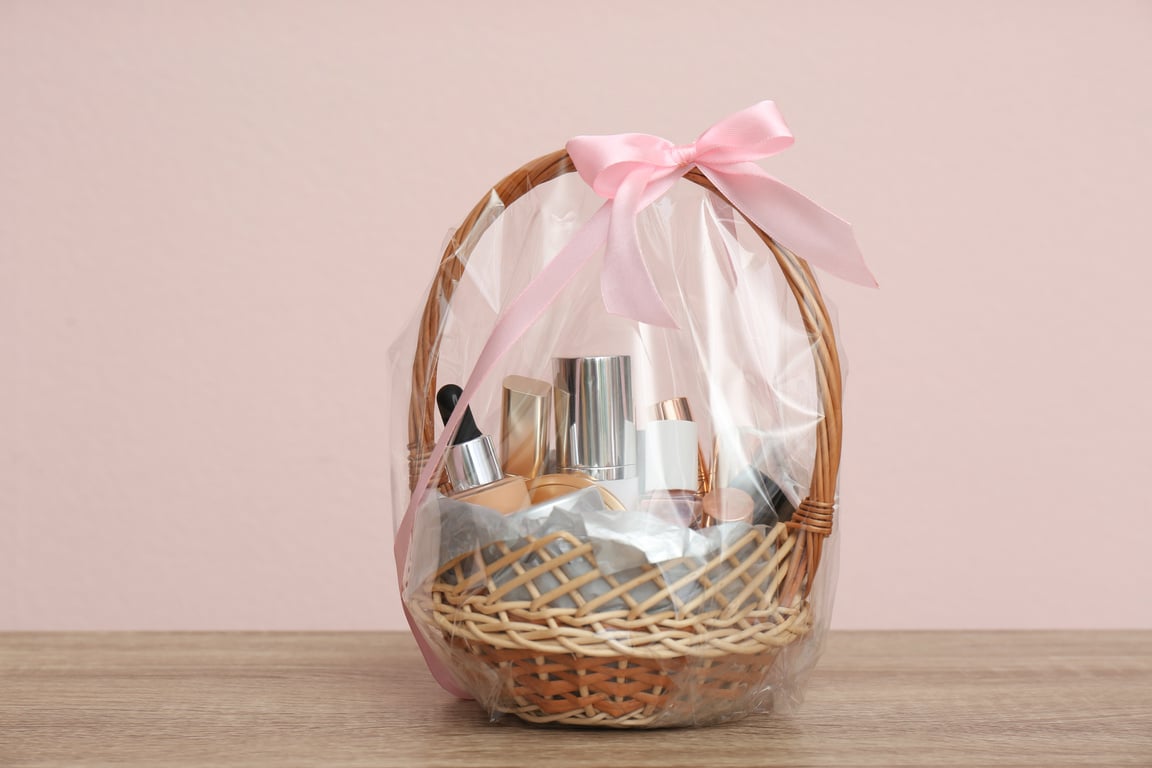 Wicker Gift Basket with Cosmetic Products on Wooden Table